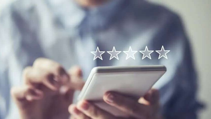 A person holding a smart phone and giving a rating for a review