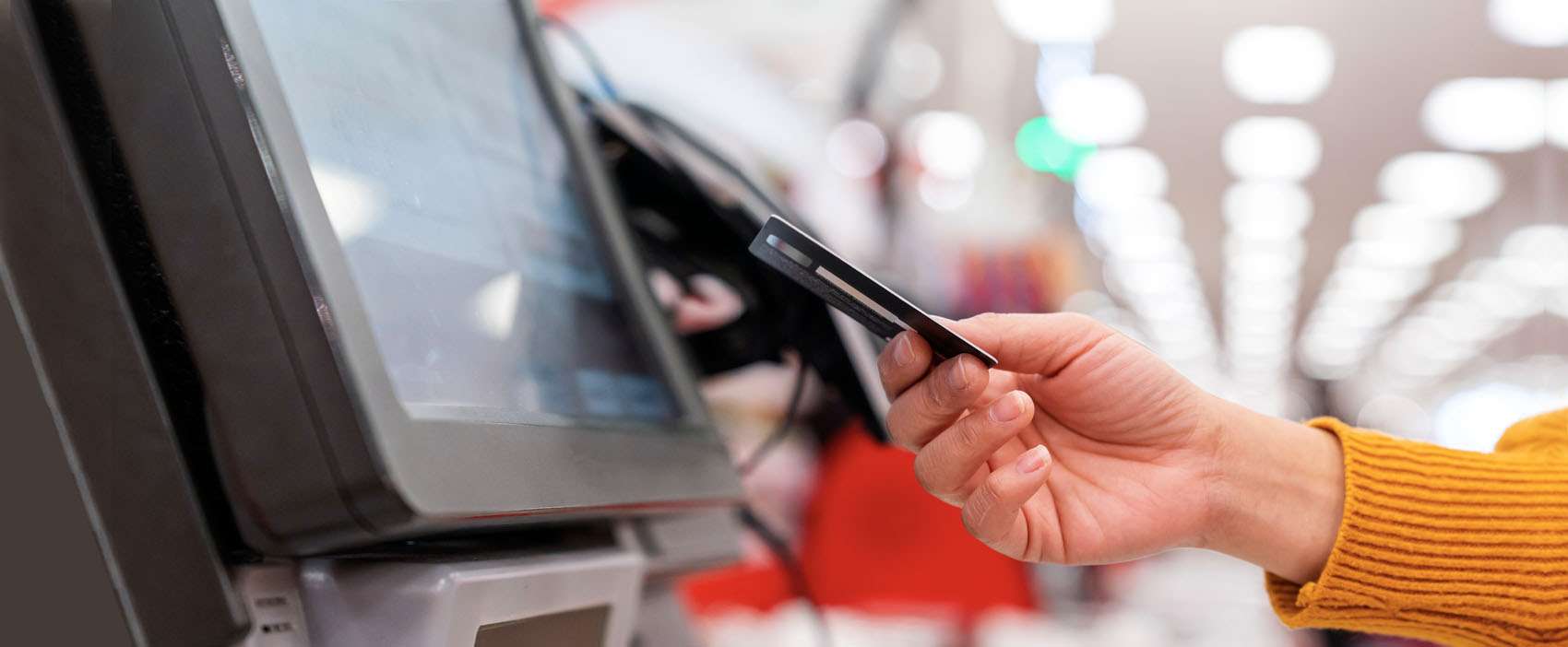 pos banner showing a consumer's hand with a credit card in it as she pays at a kiosk