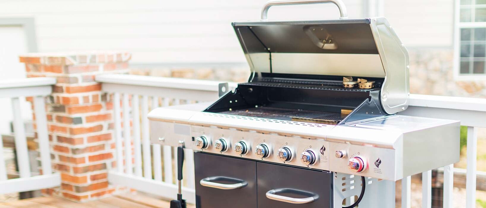 Large grill with the cover open on a home's deck